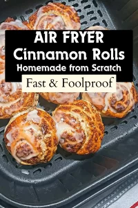 Seven golden-brown, homemade cinnamon rolls topped with sweet glazed, perfectly baked and arranged inside a black air fryer basket.