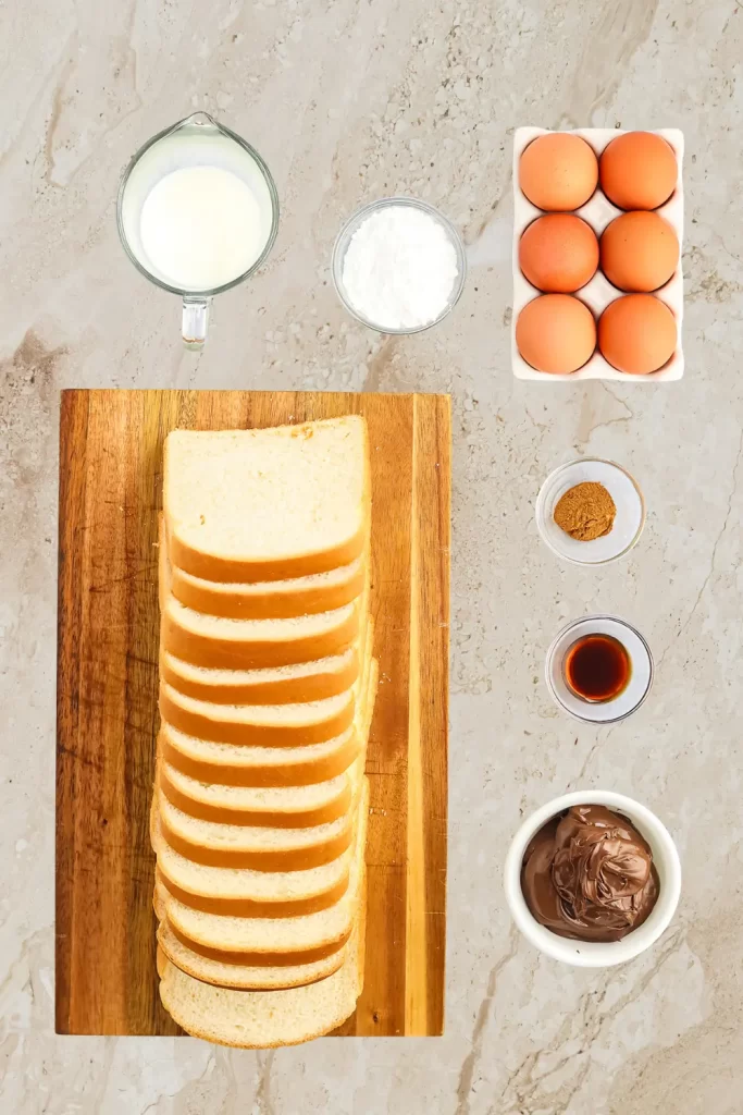 Ingredients for French toast roll ups including white bread, eggs, milk, sugar, cinnamon, vanilla extract, and chocolate hazelnut spread